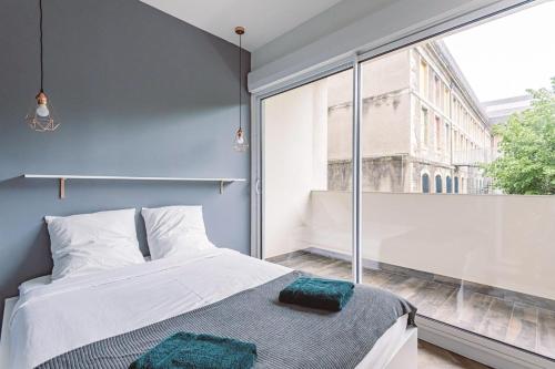 une chambre avec un lit et une grande fenêtre dans l'établissement HENRI au pied de la cathédrale., à Reims