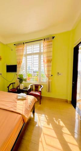 a bedroom with yellow walls and a bed and a chair at GUEST HOUSE PHÚ XUÂN in Thôn Lại Thê