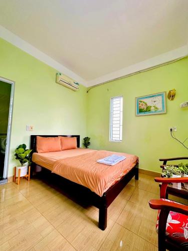 a bedroom with a bed with orange sheets and green walls at GUEST HOUSE PHÚ XUÂN in Thôn Lại Thê