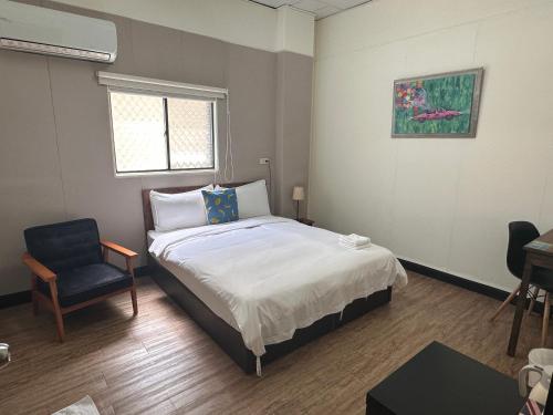1 dormitorio con 1 cama y 1 silla en OC Hostel, en Tainan
