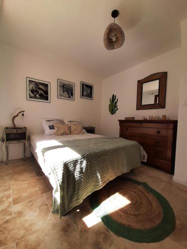 une chambre avec un lit, une commode et un miroir dans l'établissement Maison au pied de la st victoire avec piscine, à Pourrières