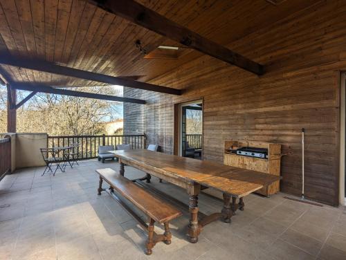 une grande terrasse avec une table et des bancs en bois dans l'établissement Le Domaine de la Croze, à Gramat