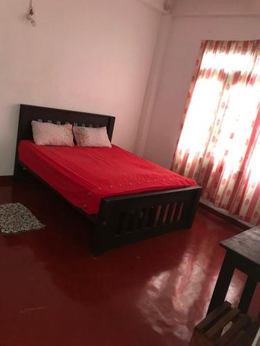 a bedroom with a bed with red sheets and pillows at Everest Rooms in Piliyandala