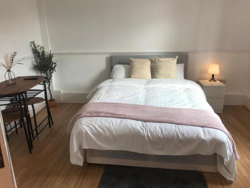 a bedroom with a large bed and a table at Modern Bromely House in BR5 in Foots Cray