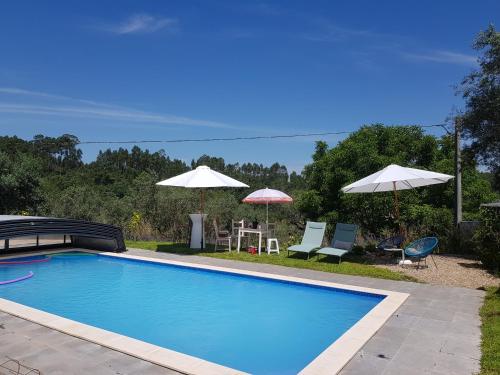 a swimming pool with two umbrellas and a table and chairs at QUINTA FENIX - Studio familial avec cuisine in Cerejeiras