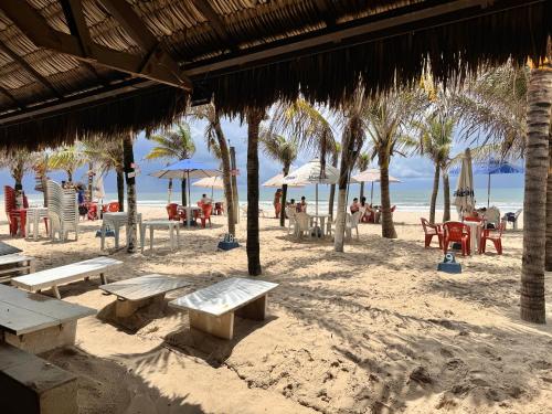 uma praia arenosa com mesas, cadeiras e guarda-sóis em Aquaville Resort em Fortaleza