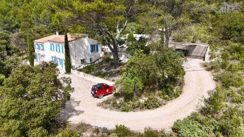 une vue aérienne sur une voiture rouge garée devant une maison dans l'établissement Mas d'Olea - heated swimming pool - airco, à Lauris