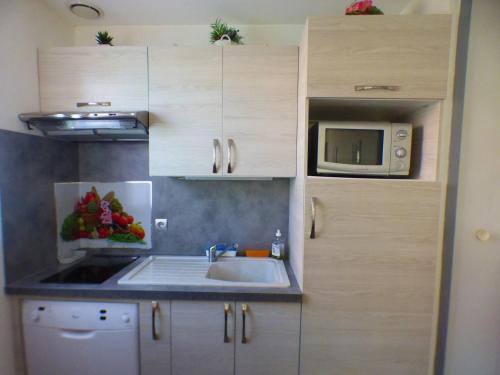 une cuisine avec un évier et un micro-ondes dans l'établissement Petite maison climatisée avec terrasse, piscine, tennis à Bormes-les-Mimosas, à 5 min de la plage - FR-1-251-815, à Bormes-les-Mimosas
