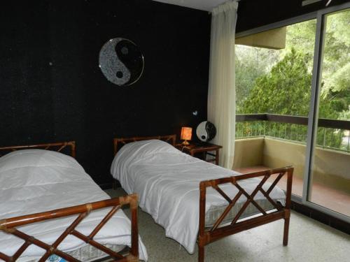 - 2 lits dans une chambre dotée d'un mur noir et d'une fenêtre dans l'établissement Appartement familial avec piscine et tennis, proche plage - 6 couchages, Bormes-les-Mimosas - FR-1-251-817, à Bormes-les-Mimosas