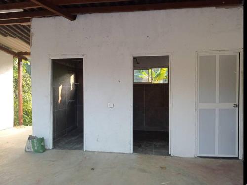 an empty room with a door and two windows at Oso Hostel Cabaña Los Linderos in Santa Marta