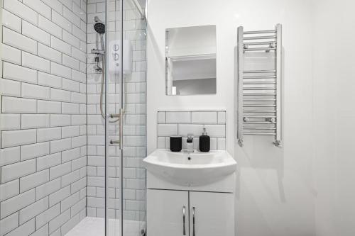 a white bathroom with a sink and a shower at Brand New 5 Bedroom House in Plymouth