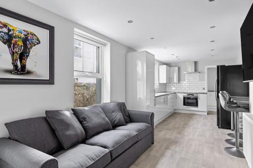a living room with a couch and a kitchen at Brand New 5 Bedroom House in Plymouth