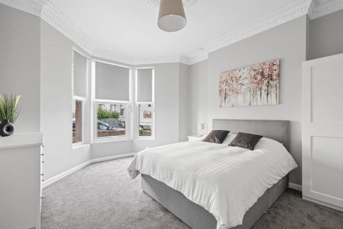 a white bedroom with a large bed and windows at Brand New 5 Bedroom House in Plymouth