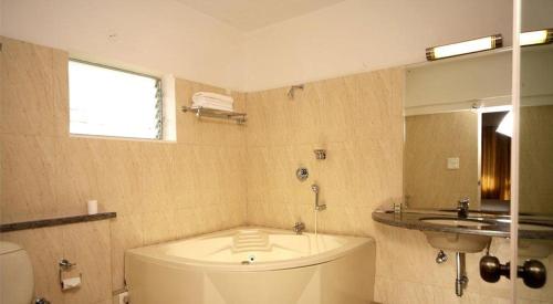 a bathroom with a tub and a sink and a toilet at Trinity Suites in Bangalore
