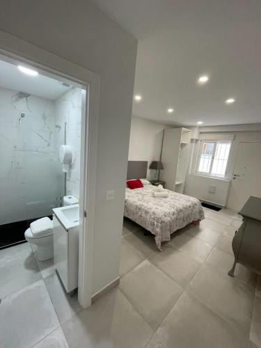 a white bedroom with a bed and a bathroom at Casa amplia ideal en pleno centro del casco histórico de Almuñecar in Almuñécar