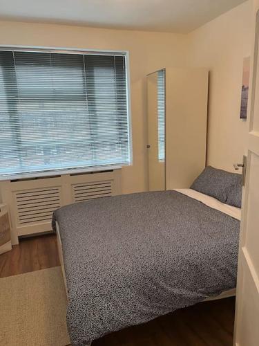 a bedroom with a bed and a large window at Flat in White city - Westfield in London