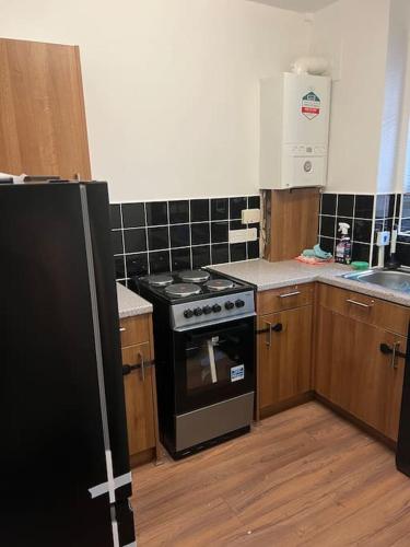 een keuken met een zwarte kachel en een wastafel bij Flat in White city - Westfield in Londen