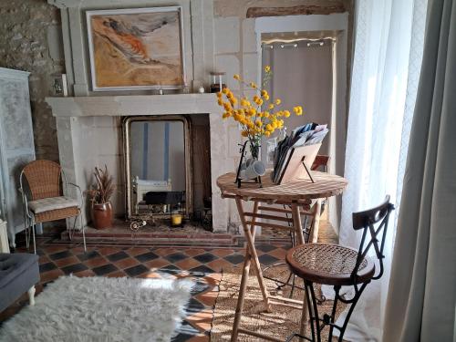 sala de estar con mesa y chimenea en Domaine de la Rose, en Vaudelnay