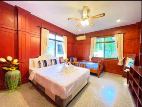 a bedroom with a bed and a ceiling fan at 高尔夫花园泳池高端6卧别墅 in Ban Huai Yai
