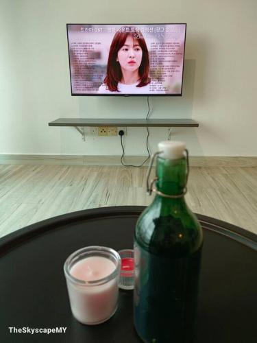 a table with a green bottle and a candle and a tv at 【HOT!】 JB Muji White Theme - Space & Comfy Suite in Johor Bahru