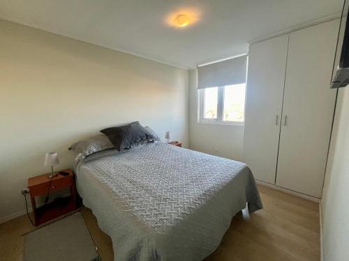 a white bedroom with a bed and a window at Departamento en Angol. in Angol