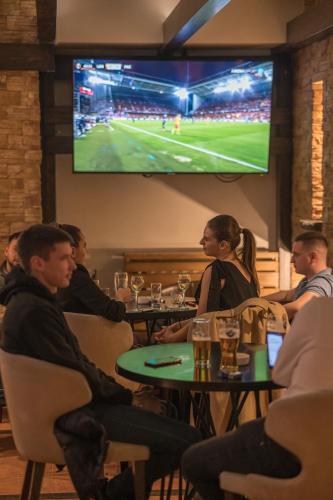 a group of people sitting at tables in a restaurant with a tv at Hotel Sun Loznica in Loznica