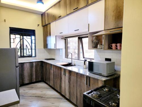 uma cozinha com armários brancos, um lavatório e um micro-ondas em Chayil Loft Bahai em Kampala