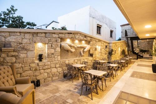 a restaurant with tables and chairs and a stone wall at Ala Da Vinci Hotel Alaçatı in Izmir