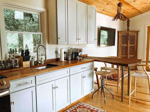a kitchen with white cabinets and a wooden table at Modern Treehouse, close to downtown and beach in Wilmington