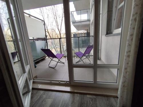 2 sillas moradas en un balcón con ventanas en Villa Natali Warszawa, en Varsovia