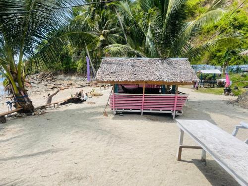 eine Hütte am Strand mit einer Bank und Palmen in der Unterkunft Northern Prince Beach Resort in General Santos