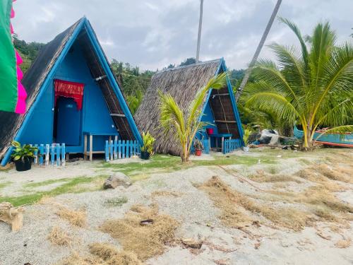 a blue house with a thatched roof on the beach at Northern Prince Beach Resort in General Santos