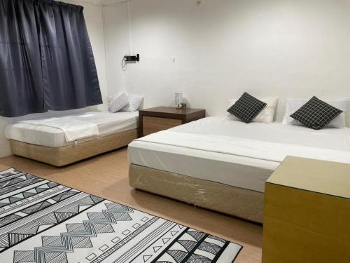 - 2 lits dans une chambre avec des tapis noirs et blancs dans l'établissement #KangaQHomestay99, à Kangar