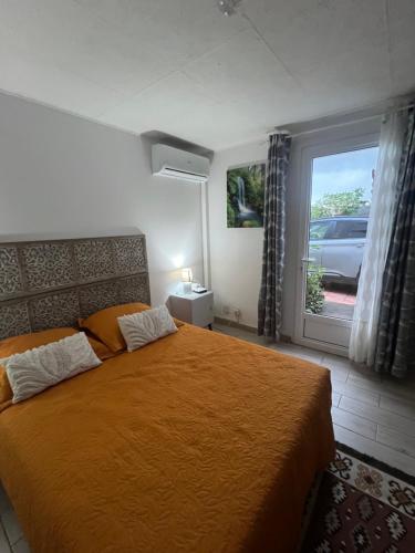 ein Schlafzimmer mit einem großen orangenen Bett und einem Fenster in der Unterkunft Appartement agréable et calme in Sainte-Suzanne