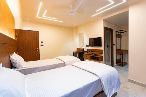 a hotel room with two beds and a television at Uphills boutique hotel in Kallar Vattiyar