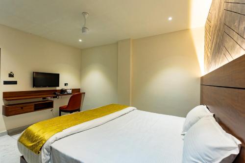 a bedroom with a bed and a desk and a television at Uphills boutique hotel in Kallar Vattiyar