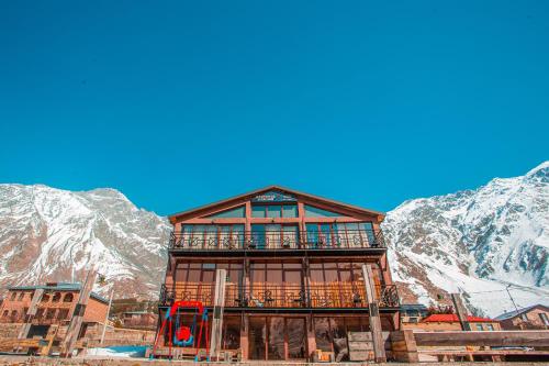 a large building with mountains in the background at Chemodann Kazbegi in Stepantsminda
