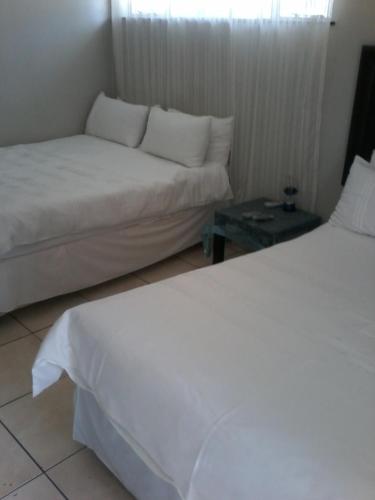 um quarto de hotel com duas camas e uma mesa em Palm Springs B and B and Self Catering em Butterworth