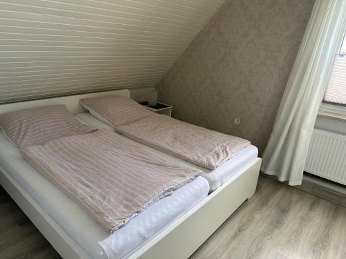 ein unmaskiertes Bett in einem Zimmer mit Fenster in der Unterkunft Ferienzimmer Becker(Nordzimmer) in Werdum