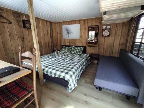 um pequeno quarto com uma cama e um sofá em "Tempat Senang" chalet on the beautiful Veluwe with airco sauna bbq jacuzzi beamer and dog em Putten