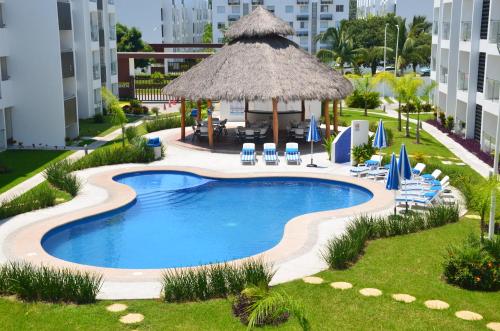 an empty swimming pool with chairs and a gazebo at Casa Parota Manzanillo in Manzanillo