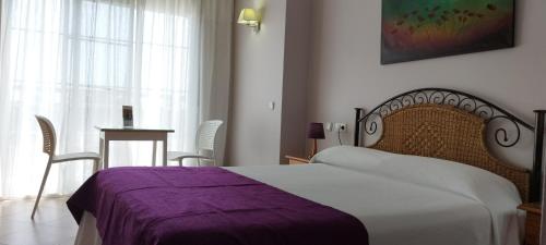 a bedroom with a bed with a purple blanket at Hotel Miraya Beach in Torre del Mar