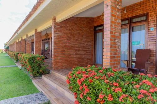 a brick building with a wooden porch with flowers at Hotel Praia dos Carneiros in Tamandaré