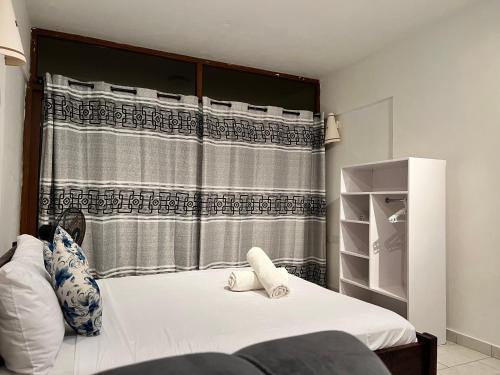 a bedroom with a bed with a shower curtain at Diani Sun Beachfront Studio in Ukunda