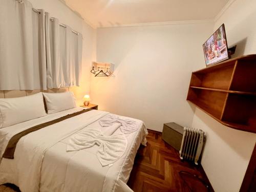 ein Schlafzimmer mit einem weißen Bett und einem Fenster in der Unterkunft Residencia Dago Suítes in Campos do Jordão
