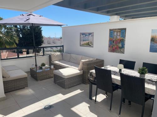 un patio con sofá y mesa con sombrilla en Casa Torremolinos en Torremolinos