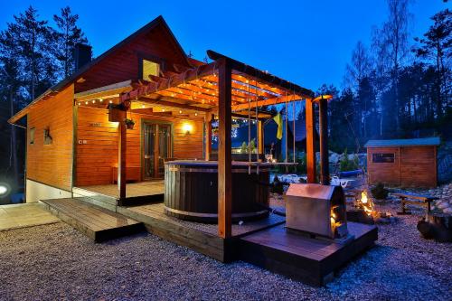 a wooden cabin with a hot tub and a grill at Domek całoroczny JELENIÓWKA na Kaszubach z balią na wyłaczność,wspólny basen i bilard z domkiem Sówka - Ostrowite Leśna Dolina in Sulęczyno