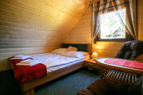 a bedroom with a bed in a wooden room at Domek całoroczny JELENIÓWKA na Kaszubach z balią na wyłaczność,wspólny basen i bilard z domkiem Sówka - Ostrowite Leśna Dolina in Sulęczyno