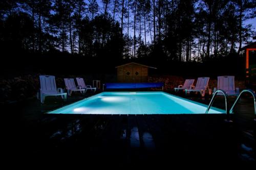 a small swimming pool with chairs and a house at Domek całoroczny JELENIÓWKA na Kaszubach z balią na wyłaczność,wspólny basen i bilard z domkiem Sówka - Ostrowite Leśna Dolina in Sulęczyno