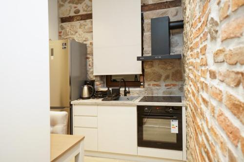 a kitchen with white cabinets and a brick wall at MONOPATI HOUSE in Mouzákion